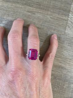 This stunning ring boasts a 7.6 carat emerald cut cultured ruby set in a beautiful sterling silver band. The vibrant pink hue of the main stone is complemented by the simplicity of the metal, creating a timeless and elegant piece of jewelry. The ring is a size 6 and perfect for those looking for a unique and eye-catching statement ring. Formal Radiant Cut Ruby Ring With Center Stone, Luxury Emerald-cut Ruby Ring, Gia Certified Emerald Cut Ruby Ring, Ruby Emerald Ring, Formal Emerald-cut Lab-created Ruby Jewelry, Emerald Cut Ruby Ring For Promise Ring, Classic Ruby Ring With Radiant Cut, Formal Pink Ruby Ring In Sterling Silver, Emerald Cut Ruby Ring With Accent Stones