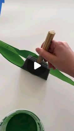 someone is painting the top of a table with green paint and a wooden stick on it