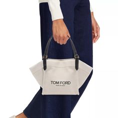 Carry your essentials in style with the Amalfi Small Canvas Tote Bag. From the Amalfi Collection by TOM FORD, this bag is made of durable canvas and features logo lettering for a chic touch. Perfect for everyday use, it's a practical and fashionable choice. Chic Canvas Bag For On-the-go, Chic Coated Canvas Bag For On-the-go, Designer Canvas Bag With Removable Pouch For Shopping, Modern Canvas Bags For On-the-go, Chic Coated Canvas Bucket Bag For Shopping, Modern Bucket Bag With Leather Trim For Shopping, Chic Coated Canvas Shoulder Bag With Logo, Canvas Bucket Bag With Removable Pouch For Shopping, Modern Leather Trim Bucket Bag For Shopping