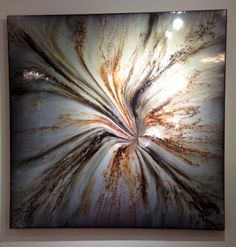 an abstract art piece hanging on the wall in a room with white and brown walls