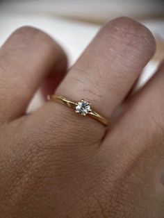 a woman's hand with a diamond ring on top of her finger, showing the side view