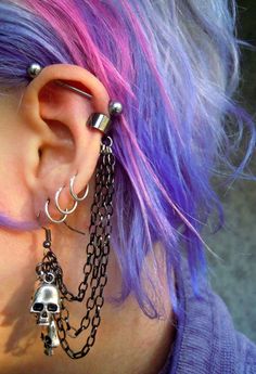 a woman with purple hair and piercings wearing chain earring designs on her ears