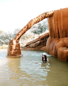 there is a woman swimming in the water with an umbrella over her head and some rocks behind her