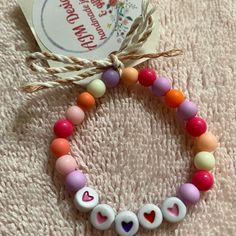 a close up of a beaded bracelet on a cloth with a tag attached to it