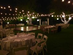 tables and chairs are set up for an outdoor event with lights strung from the ceiling