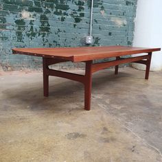 a wooden table sitting in front of a brick wall