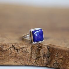 This deep, blue Lapis Lazuli ring will empower you. Wear it alone or as a centerpiece to a hand of rings - the square is such a strong shape, and is perfectly enhanced here in this .925 Sterling Silver, Lapis Lazuli Ring. This deep blue Lapis Lazuli Ring is perfectly unisex, with a minimal, .925 Sterling Silver Split Shank and Gorgeous AA Blue Lapis Lazuli centerpiece cabochon. Choose your size - all traditional silversmithing is done in my Baltimore, MD studio AA Lapis Lazuli - 12X12 mm  Ring Top 16X16mm .925 Sterling Silver  Choose your size below - larger and smaller sizes are available upon request. Lapis Lazuli is one of the most sought-after stones in use since man's history began. It's deep, celestial blue remains the symbol of royalty and honor, gods and power, spirit and vision. I Blue Square Cut Ring As A Gift, Sterling Silver Promise Ring With Rectangular Stone, Fine Sterling Silver Rings With Rectangular Stone, Stackable Rectangular Sterling Silver Jewelry, Hallmarked Square Cut Ring As A Gift, Sterling Silver Rings With Rectangular Stone, Fine Jewelry Sterling Silver Ring With Rectangular Stone, Sterling Silver Stackable Rectangular Jewelry, Sterling Silver Rings With Rectangular Stone For Gift