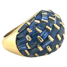 Ravishing 18 karat yellow gold and sapphire cocktail ring, circa 1970s. Crafted in 18 karat yellow gold, of bombé design, the dome fully set with numerous sapphire baguettes and trapezes of a deep yet luminous blue shade. The way the sapphires are set - all aligned diagonally - renders this ring very stylish and unique. This statement ring is perfect for day and evening wear and in good vintage condition. Ring size: 52 (EU) / 6.5 (US) Width at head: circa 1.7 cm / 0.67 in Width of band: circa 4.2 mm / 1.6 in Maker's mark: RCM Assay mark: 750 Sapphire Cocktail Ring, Cocktail Ring, Cocktail Rings, Statement Ring, Evening Wear, Statement Rings, 1970s, Jewelry Rings, Ring Size