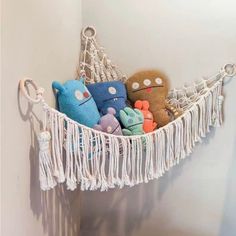 some stuffed animals are in a hammock hanging on the wall above a toilet