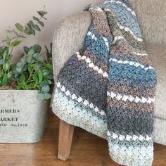 a chair with a blanket on it next to a potted plant