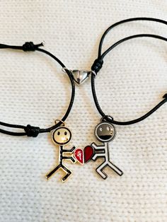 two bracelets that have charms on them, one with a man and the other with a heart