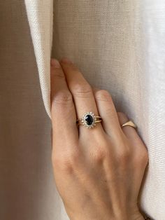 a woman's hand with a ring on her finger, peeking out from behind a curtain