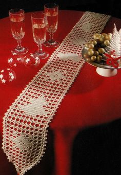 a red table topped with two wine glasses and a white doily