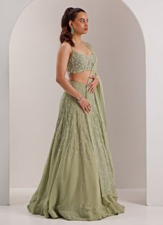 Embrace a look of sophistication with this beautifully designed Mint Green Embellished Organza Lehenga, perfect for making a statement at any celebration. Crafted from lightweight organza, the mint green lehenga features intricate crystal and cut dana embroidery, adding a touch of sparkle. Paired with a beautifully embroidered scoop neck blouse and a sheer dupatta that drapes gracefully. Ideal lehenga set for Mehndi, Sangeet, or as wedding guest attire. Composition : Lehenga, Blouse, Dupatta - Organza and Shantoon Care: Dry Clean Only and Vacuum Storage This product can be customized for sleeves, blouse length and neckline Delivery : 6-8 weeks as the product is hand crafted. Check Size Guide or choose MySize for free customisation (All Sizes above XL can be made at 15% additional cost) For Lengha Blouse Designs Back, Lehenga Wedding Guest, Nepali Clothing, Sage Green Lehenga, Mint Green Lehenga, Lengha Blouse Designs, Sheer Dupatta, Wedding Guest Attire, Scoop Neck Blouse