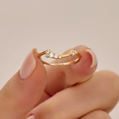 a woman's hand holding a gold ring with three small diamonds on the side