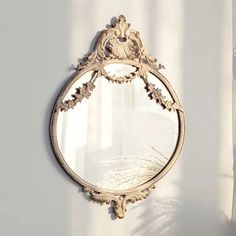 a mirror hanging on the side of a wall next to a white curtain and window