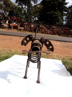 a metal sculpture sitting on top of a white sheet in the grass next to a road