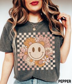 Our cute and retro flower smiley face graphic tee features a distressed floral happy face on a checkered background design. This oversized t-shirt is available in a variety of colors and you'll love the comfortable material of the Comfort Colors fabric. It ensures a soft and comfortable feel that will keep you feeling good all day long. ✩ Smiley Face Shirt, Flower Shirt, Retro Smile Face, Trendy Vintage Graphic Tee, Checkered Comfort Colors T-shirt, Plus Size Happy Face Tshirt SIZE UP for an OVE Affordable Fun Smiley Face T-shirt, Spring Crew Neck Top With Smiley Face, Spring Smiley Face Crew Neck Top, Cute Spring Tops With Smiley Face, Cute Smiley Face Tops For Spring, Cute Smiley Face Top For Spring, Spring Smiley Face Short Sleeve T-shirt, Spring Tops With Smiley Face, Short Sleeve, Short Sleeve Tops With Smiley Face For Spring