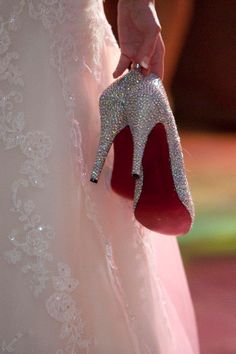 a close up of a person's hand holding a pair of high heeled shoes