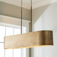 a wooden light fixture hanging from a ceiling in a room with white walls and windows