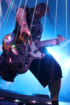 a man with long hair playing an electric guitar