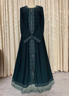 Elegant beautiful embroidery and stonework dark teal green (bottle green) abaya with a contrast color front double bottom embroidered finish.  Soft, lightweight flowy fabric suitable for all weather conditions, best pick for hot summer temperatures.  Front closed burqa with decorative shiny stone buttons in super high premium quality fabric. Available in size 52. (This abaya does not come with a matching scarf.) Green Abaya, Stone Buttons, Dark Teal Green, Summer Temperature, Head Coverings, Green Bottle, Hijab Scarf, Flowy Fabric, Under Dress