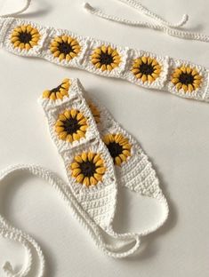 two crocheted sunflowers are sitting next to each other on a white surface