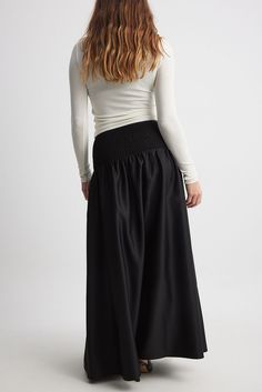 This maxi skirt features a flowy fit and a volume design. It has satin material and a stretchy, wide smocking at the waist. Luxury Satin Finish Flowy Maxi Skirt, Luxury Voluminous Maxi Skirt, Elegant Black Maxi Dress With Gathered Waist, Black Maxi Dress With Gathered Waist, Black Maxi Dress With Pleated Waist, Elegant Flowy Maxi Skirt With Gathered Waist, Ruched Long Voluminous Skirt, Voluminous Ruched Long Skirt, Voluminous Maxi Skirt With Elastic Waistband