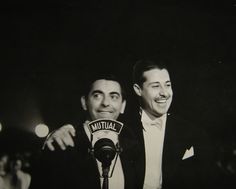 two men standing next to each other in front of microphones