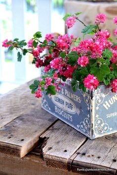 pink flowers are in a metal container on a wooden table with the words fabulous flowers written below it