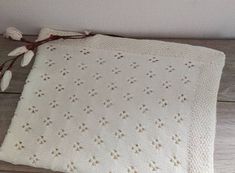 a white crocheted blanket sitting on top of a wooden floor next to a plant