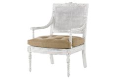 a white wicker chair with a tan cushion on it's seat pad and back