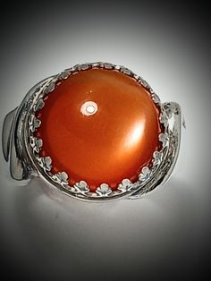 ORANGE MOONSTONE, Ring, Very Rare Quality! 11.5mm, AAA. Gem, Sterling Silver, Size 61/2, RC3.orang.ms.Please tell me your size. RING BOX#4 This is the only orange moonstone I have in my collection. The stone is rare and beautiful.  VERY RARE QUALITY GREAT CHATOYANCY! GREAT POLISH! GREAT CUT GREAT COLOR All of my stones are hammer set. We design jewelry to last a lifetime. This ring is excellent and strong. It should last forever.  Thank you for considering my work. LuvBruce Location: Celtic Jewelry Gift Moonstone Ring With Round Accent Stones, Elegant Amber Crystal Ring, Anniversary Cabochon Gemstones, White Gold Round Cabochon Gemstones, Elegant Round Orange Gemstones, Orange Round Jewelry With Accent Stones, Round White Gold Polished Cabochons, Polished White Gold Cabochons, Silver Moonstone Ring With Cabochon Cut