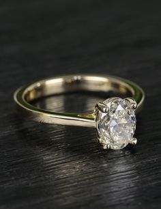 an engagement ring with a single diamond in the center on a wooden surface, close up