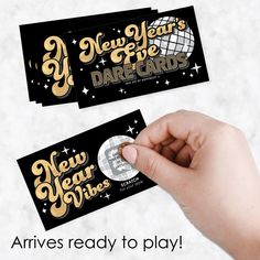 two new year's eve cards being held by a person with a ring on their finger