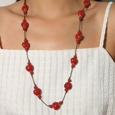 a woman wearing a necklace with red beads