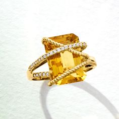 a fancy ring with an orange stone surrounded by white diamonds on a light background,