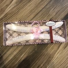 three white candles in a pink box on a wooden table with a ribbon tied around it