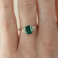 a woman's hand with an emerald and diamond ring