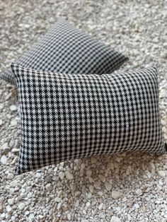 two black and white checkered pillows sitting on top of gravel next to each other