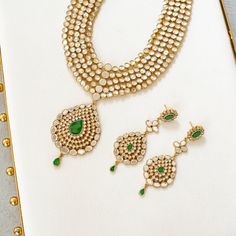 An heirloom of divinity, crafted through the ages! Introducing an opulent fiver-layer kundan mala, adorned with a magnificent emerald stone centerpiece that exudes timeless elegance, this set blends the regal charm of kundan with the vibrant allure of emeralds. A masterpiece of craftsmanship, it promises to elevate any occasion with its majestic allure. The listing includes long mala and a pair of matching earrings. Gold-plated on high-quality brass as base metal. Made by order. Kindly allow 5-7 Elegant Hand Set Kundan Necklace For Rituals, Kundan Jewelry Sets For Diwali Rituals, Emerald Chandbali Temple Jewelry, Elegant Kundan Jewelry For Rituals, Diwali Kundan Necklace For Rituals, Festive Kundan Emerald Necklace With Intricate Design, Elegant Kundan Necklace For Rituals, Emerald Bridal Necklace For Celebration In Temple Style, Festive Emerald Jewelry Sets