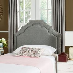 an upholstered headboard in a bedroom with curtains and pillows on the bed