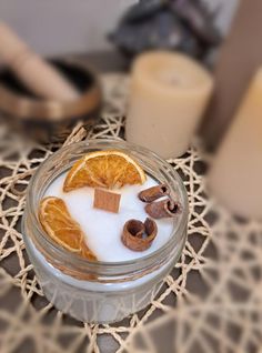 an orange slice in a glass bowl with milk and cinnamons on the table next to candles