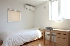 a bedroom with a bed, desk and air conditioner on the wall above it