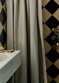 a black and white checkered shower curtain next to a bathroom sink with soap on it