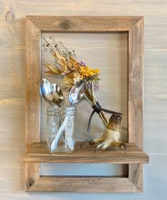 a wooden shelf with some flowers and spoons on it