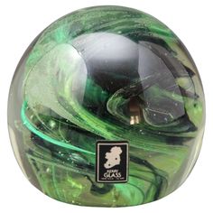 a close up of a green and black glass ball on a white background with the words cia's