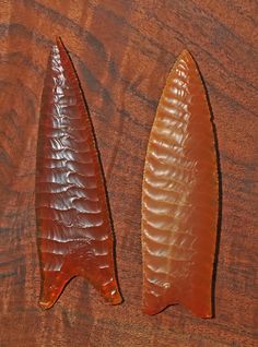 two pieces of glass sitting on top of a wooden table next to another piece of wood