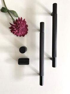 three different types of pens and a flower on a white surface with one pink flower