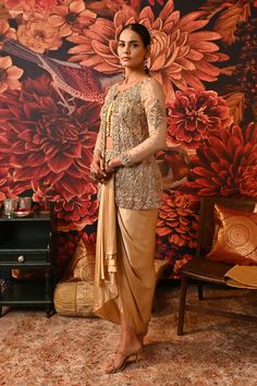 This Gold Co-ord set is the way to hop on the bold and versatile trend, that modern women prefer. Paired with a waistcoat style top along with a heavily embroidered jacket detailed with silver and golden hue and for the bottom a dhoti-style draped skirt giving you that chic regal look. Gold foil printed sleeveless blouse with embroidered border and handmade buttons on the centre front Front Open jacket with gold foil print heavily embellished with dabka & nakshi Waistcoat style bustier Dhoti-sty Traditional Silk Sets For Evening, Traditional Silk Evening Sets, Elegant Gold Sets With Resham Embroidery, Elegant Brocade Pre-draped Saree For Designer Wear, Elegant Unstitched Sets With Gold Embroidery, Elegant Festive Brocade Pre-draped Saree, Elegant Sets With Gold Embroidery For Diwali, Elegant Festive Sherwani In Chinon, Traditional Formal Sharara With Gold Embroidery